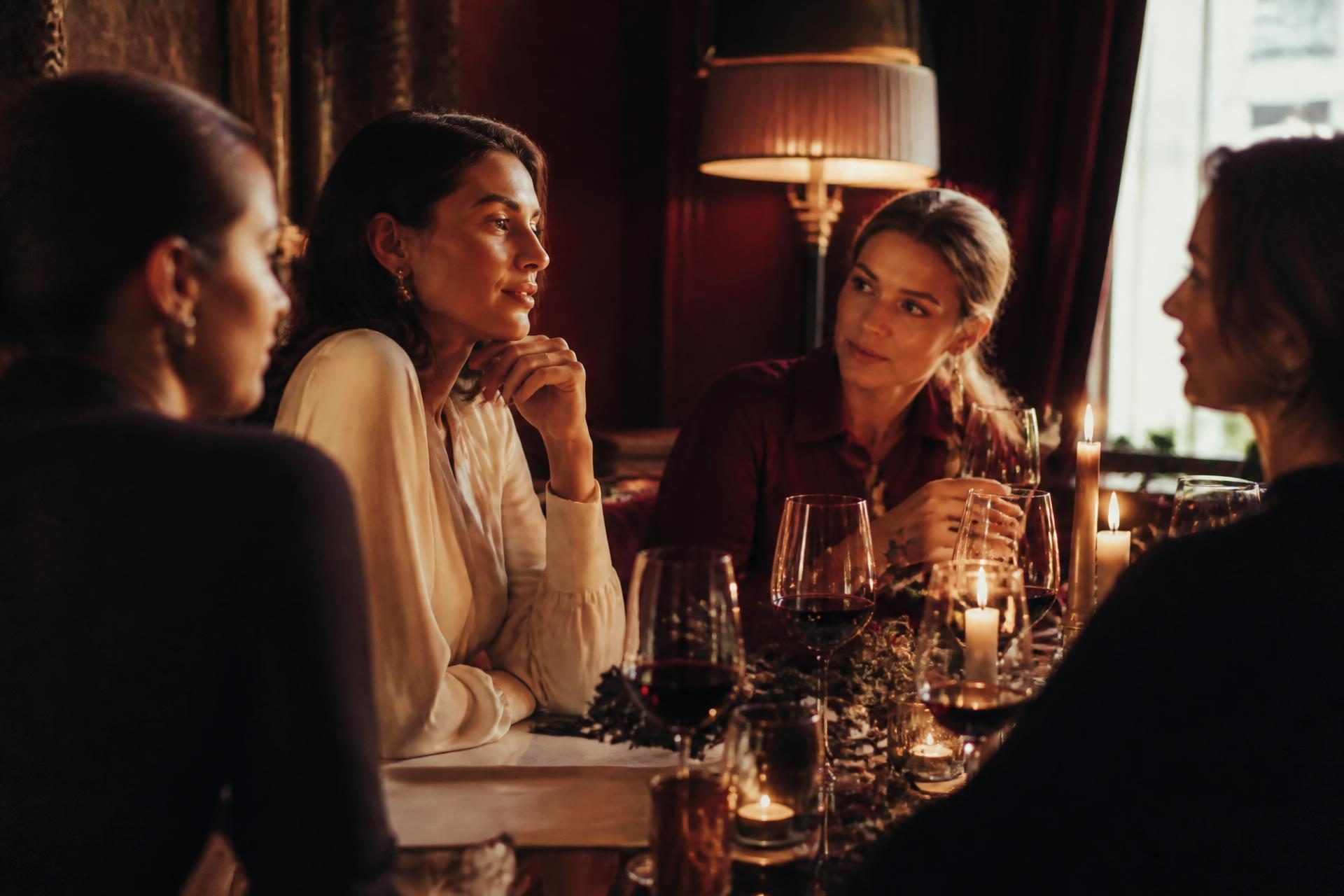 Mulheres reunidas à mesa com taças de vinho